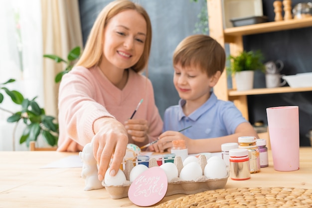 Sonriente Joven Madre Y Su Hijo Sentados A La Mesa Y Disfrutando De