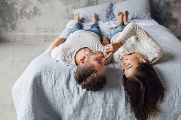 Sonriente Joven Pareja Acostada En La Cama En Casa En Traje Casual