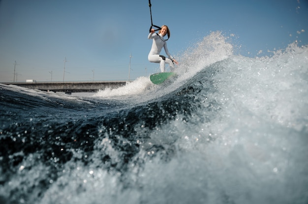 Sonriente Mujer Rubia En Traje De Baño Blanco De Pie En El Wakeboard Sosteniendo Una Cuerda En