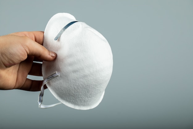 Sosteniendo una mascarilla médica moderna blanca Foto gratis