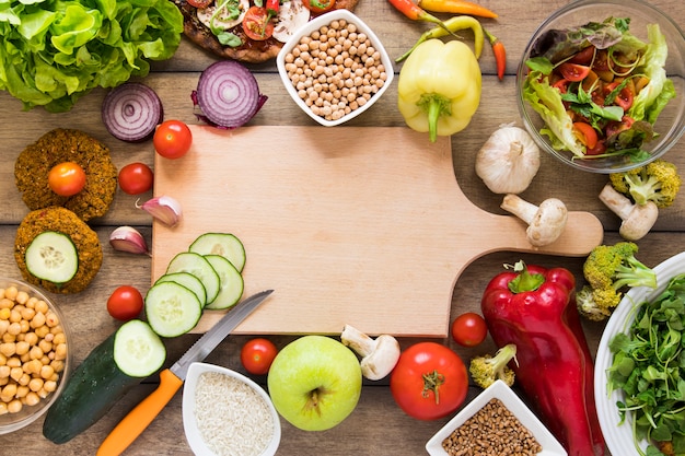 Tabla de cortar rodeada de vegetales Foto gratis