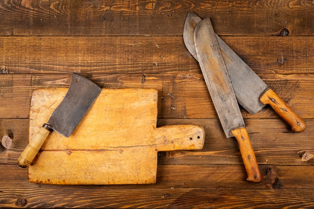 Tabla de cortar con viejos cuchillos de cocina en mesa de madera | Foto Premium