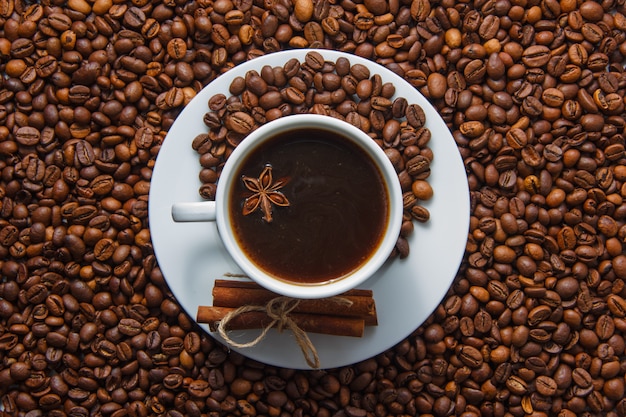 Una taza de café y canela seca con granos de café en el fondo. vista ...