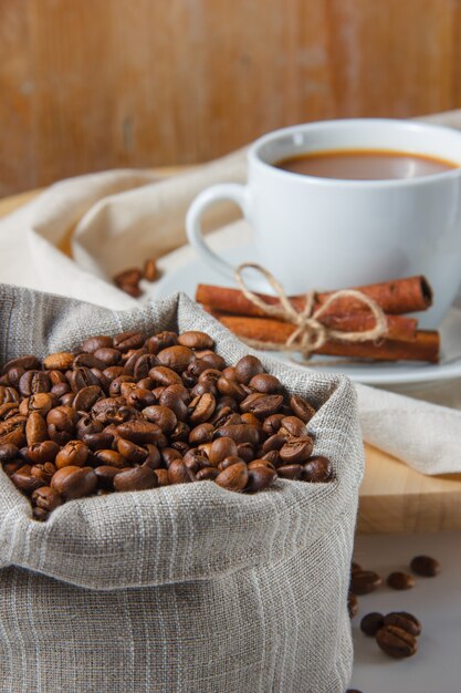 Una taza de café con granos de café en un saco, vista