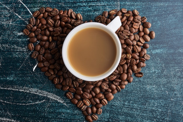 Una taza de café en granos en forma de corazón. Foto gratis