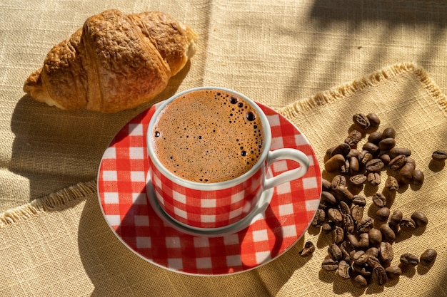 Taza De Croissant De Caf Y Granos De Caf Iluminados Por La Luz Del