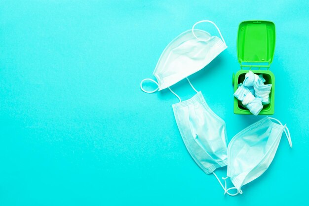 Tirar una mascarilla médica en un contenedor verde para reciclar sobre