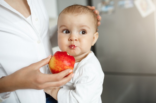 Toma recortada de la madre dando a bebé una rodaja de manzana Foto gratis