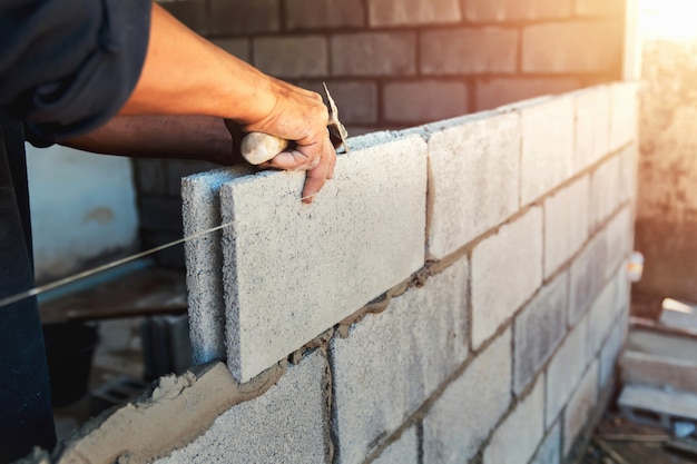 Trabajador construyendo ladrillos de pared con cemento | Foto Premium