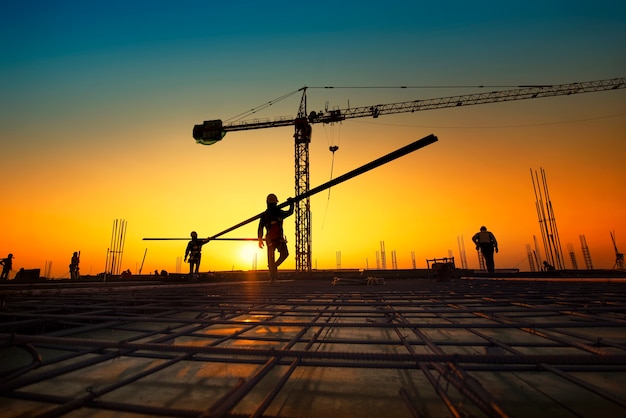 Trabajadores de la construcción de la silueta que fabrican barras de refuerzo de acero en la construcción