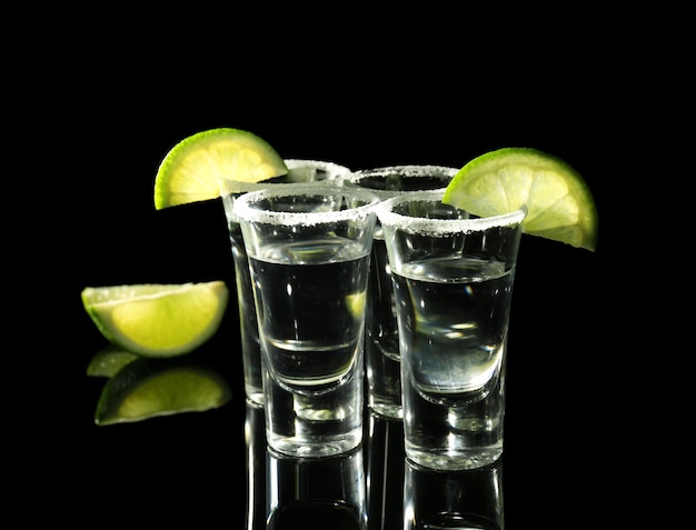 Tragos De Tequila Con Jugosas Rodajas De Limón Y Sal Sobre Fondo Negro Foto Premium