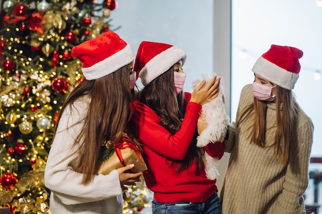 Tres chicas y un terrier posando para la cámara en la víspera de año nuevo. navidad durante el coronavirus, concepto Foto gratis