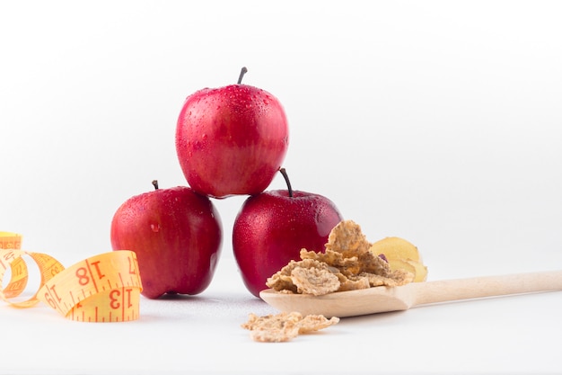 Tres manzanas con cinta métrica y cereales. Foto gratis