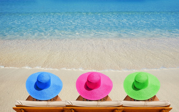 Tres mujeres en la playa con sombreros brillantes viajando en vacaciones Foto Premium 