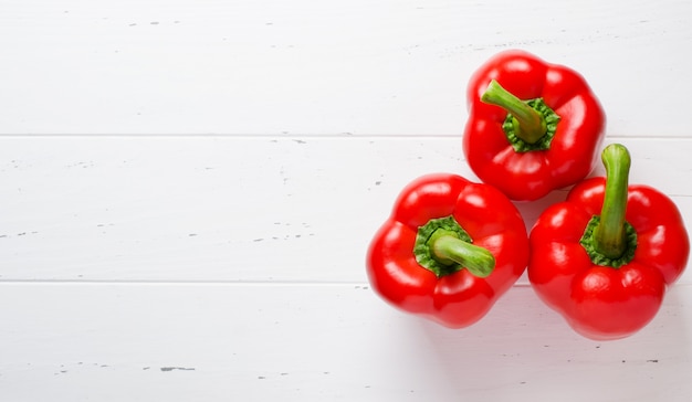 Tres Pimientos Rojos Maduros Fondo De Madera Blanca Foto Premium