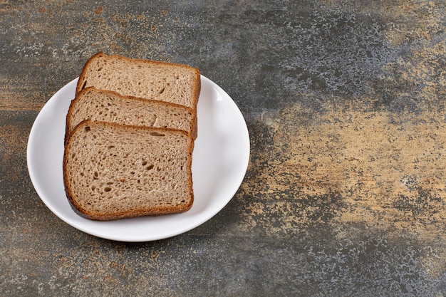 Tres Rebanadas De Pan Negro En Un Plato Blanco Foto Gratis