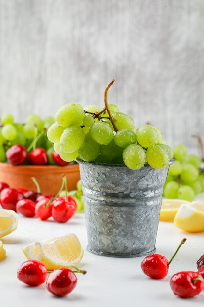 Uvas verdes con rodajas de limón, cerezas en mini cubo y tazón sobre