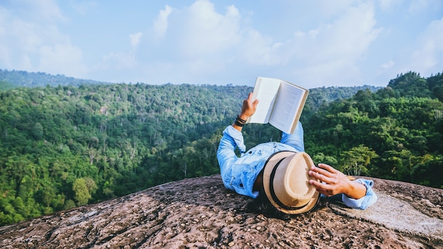 El viaje asiático del hombre se relaja en el día de fiesta dormir relajarse leer libros en acantilados rocosos. en el verano de montaña | Foto Premium