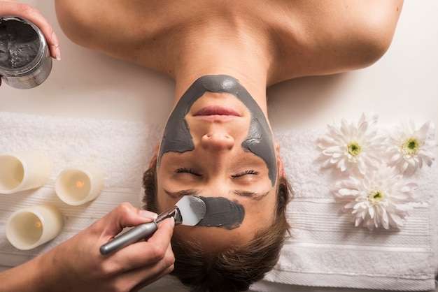 Vista de Ã¡ngulo alto de una mujer que recibe mÃ¡scara facial en el salÃ³n de belleza