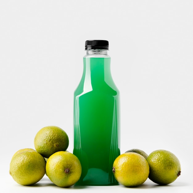 Vista Frontal De La Botella De Jugo Verde Con Lata Y Limas | Foto Gratis