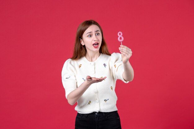 Vista Frontal Joven Mujer Sosteniendo Pegatina Rosa Sobre Fondo Rojo Sensual Igualdad Compras 8033