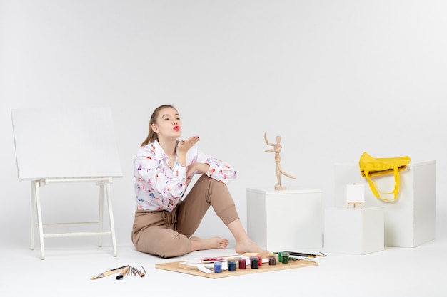 Vista Frontal Mujer Joven Sentada Con Pinturas Y Caballete Para Dibujar Sobre Fondo Blanco