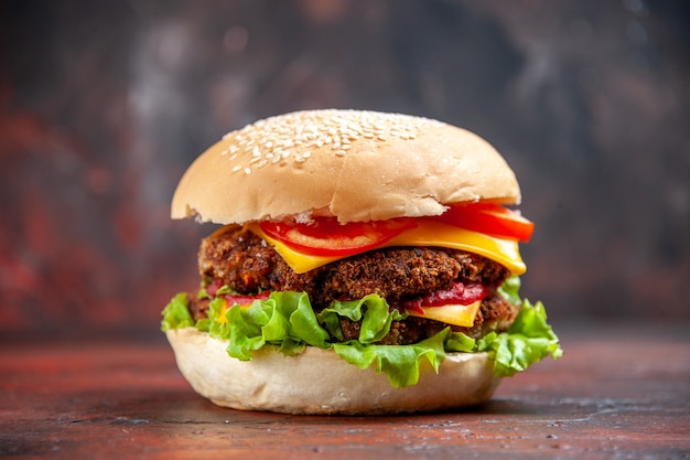 Vista frontal sabrosa hamburguesa de carne con queso y ensalada en el fondo oscuro Foto gratis