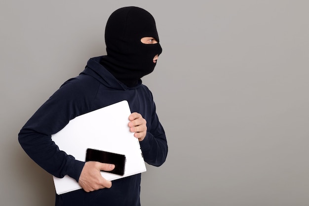 Vista lateral de un delincuente que escapa con una computadora portátil robada Foto gratis