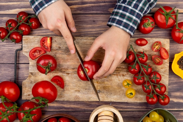 Vista Superior De Manos De Mujer Cortando Tomate En Tabla De Cortar Con Cuchillo Y Pimienta