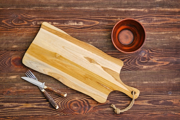 Vista Superior Del Tablero De Madera De Corte Vac O Con Cuenco De Arcilla Y Tenedor Con Cuchillo