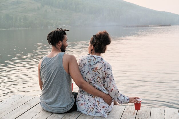 Vista Trasera De La Joven Pareja Abrazándose Y Disfrutando De La Hermosa Vista Del Lago Mientras 