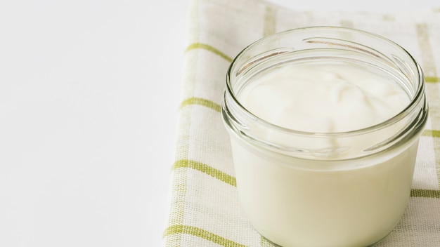 Yogur en tarro de cristal en la servilleta sobre el fondo blanco Foto gratis