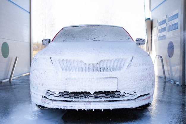 Autolavaggio con sapone e acqua ad alta pressione. la macchina è completamente sapone Foto Premium