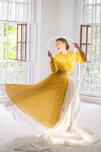 Ballerina in un abito giallo fa pa tenendo un cerchio incandescente nelle sue mani. Foto Premium