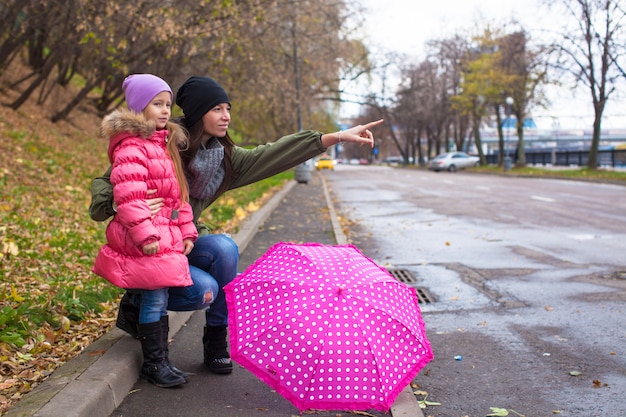 Bambina e sua madre che camminano con l'ombrello in una giornata piovosa Foto Premium