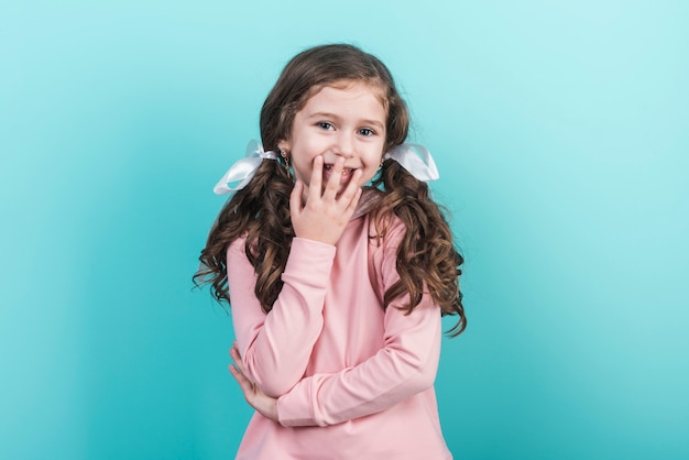 Bambina sveglia che sorride sulla priorità bassa blu Foto Gratuite