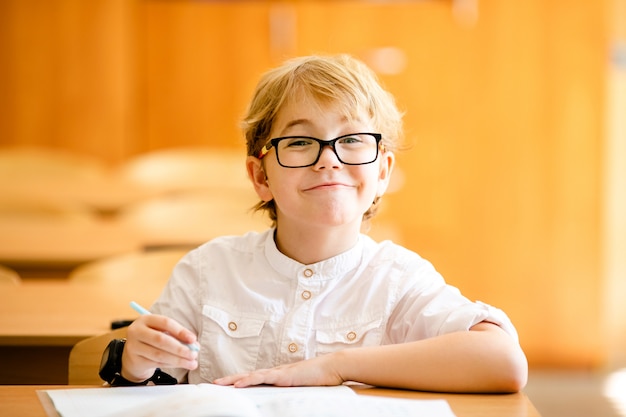 Bambino di sette anni con gli occhiali a scrivere i compiti a ...