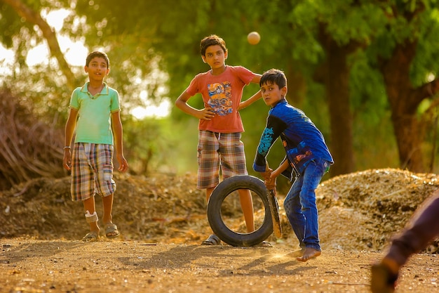 Bambino indiano rurale che gioca cricket su terra Foto Premium