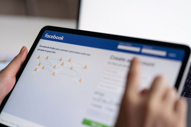 Bangkok, thailandia - 4 marzo 2019: mano sta premendo lo schermo di facebook su apple ipad pro, i social media stanno usando per la condivisione delle informazioni e il networking. Foto Premium