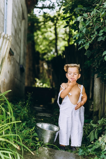 Bel ragazzo con i capelli bianchi e una combinazione si gioca con un secchio d'acqua Foto Premium