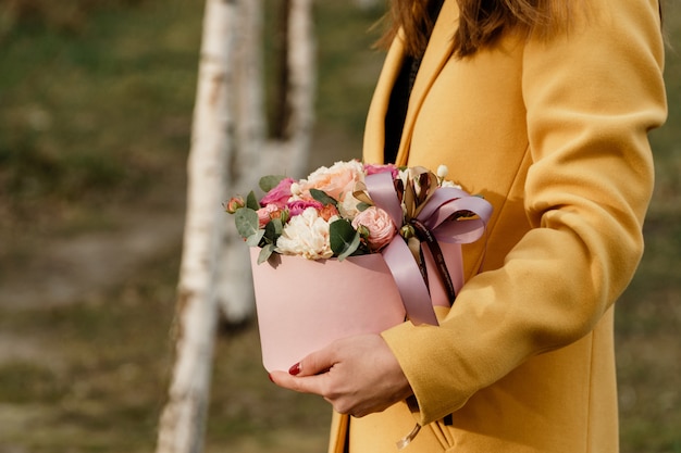 Bella donna che tiene scatola rosa con fiori. regalo per la festa della donna. Foto Premium