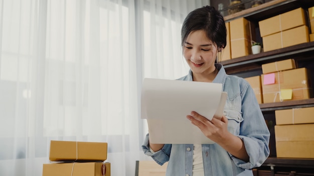 Bello giovane proprietario di donna asiatico astuto di affari dell'imprenditore delle pmi che controlla prodotto sulle azione Foto Gratuite
