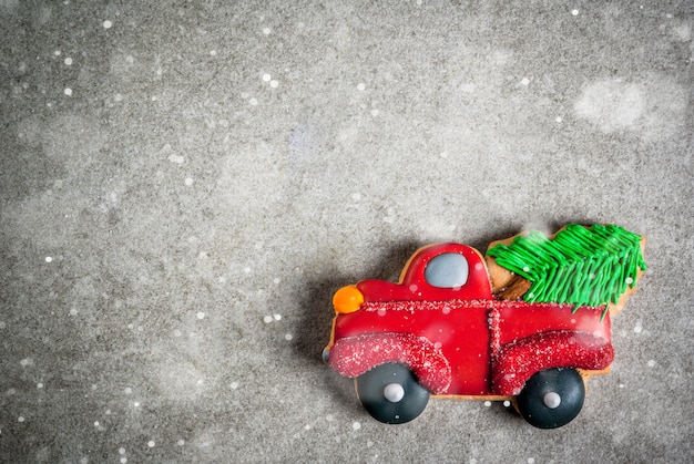 Biscotti di panpepato colorati fatti in casa di natale, a forma di auto con un albero di natale sul tavolo di pietra grigia. vista dall'alto, copyspace Foto Premium
