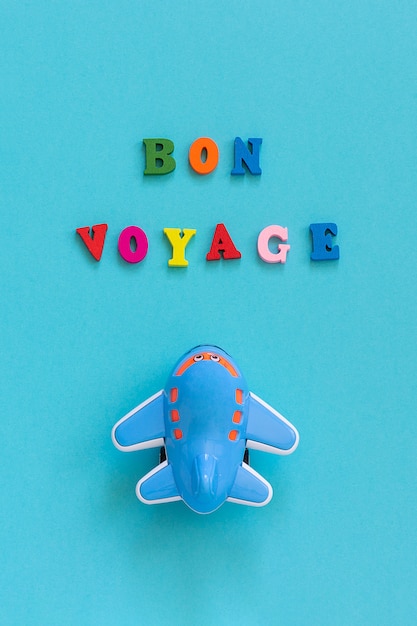 Buon viaggio e divertente giocattolo aereo per bambini su sfondo blu. concetto di viaggio, turismo Foto Premium