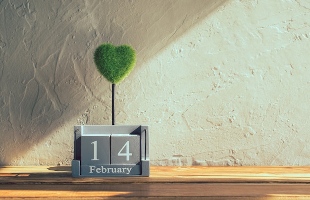 Calendario di legno d'annata per il 14 febbraio con cuore verde sulla tavola di legno Foto Premium