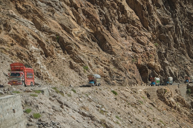 Camion pakistani che viaggiano su strada asfaltata lungo la montagna vicino alla scogliera in autostrada karakoram. Foto Premium