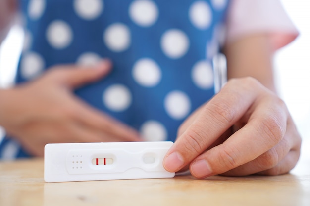 Chiuda in su della giovane donna che controlla il risultato del test di gravidanza. Foto Premium