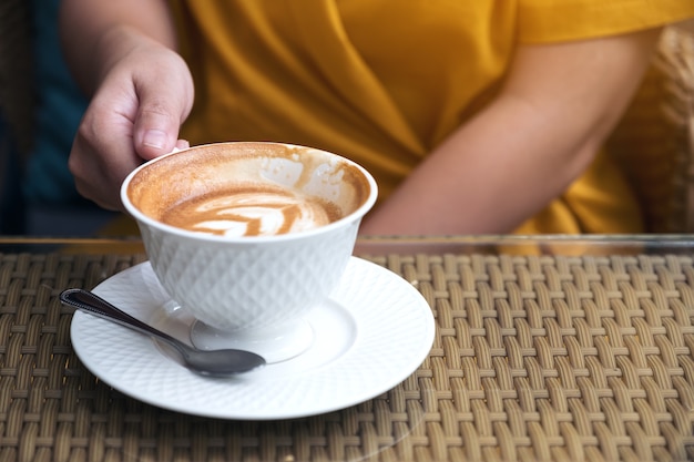 Chiuda sull'immagine di una donna che tiene le tazze di un caffè macchiato in caffè Foto Premium