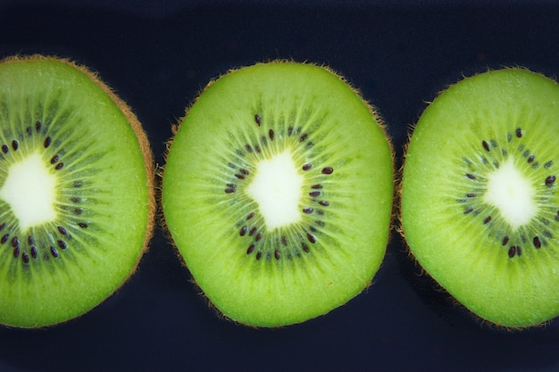 Close up fette organiche kiwi su sfondo nero Foto Premium