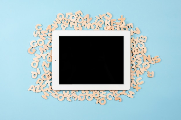 Compressa digitale con display nero su più lettere di legno su sfondo blu Foto Gratuite